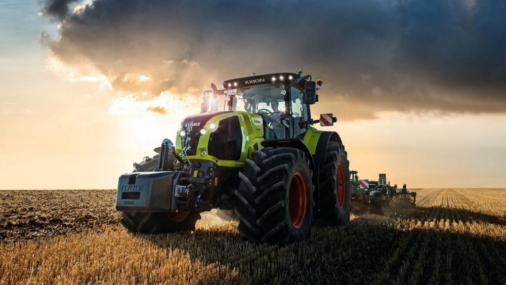 Tractor with trailer of Claas company drives on a road in an agricultural area