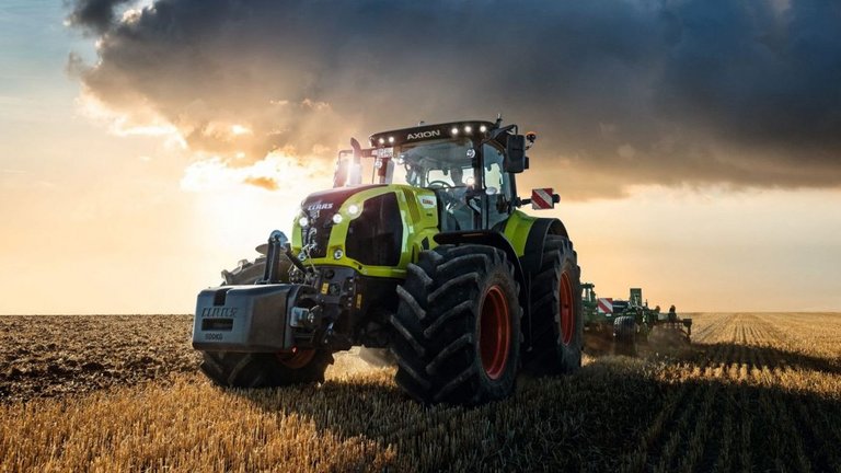 Tractor with trailer of Claas company drives on a road in an agricultural area